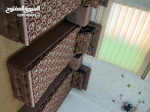 غرفة نوم شبابيه مكونه من ثلاثة تخوت ويوجد خزانه لون خشبي
