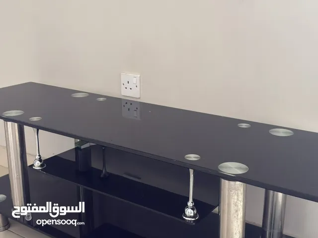 طاولة تلفزيون زجاجية عصرية بتصميم أنيق أسود داكن مع حواف لون فضي حديدي يمكن التفاوض