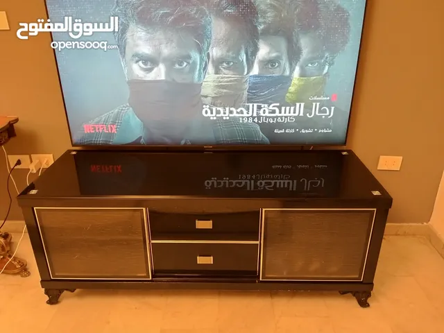 طاولة تلفزيون لون اسون بحالة ممتازة للبيع درجين وسطانيات واماكن تخزين جانبية سطح زجاجي وارفف زجاجية