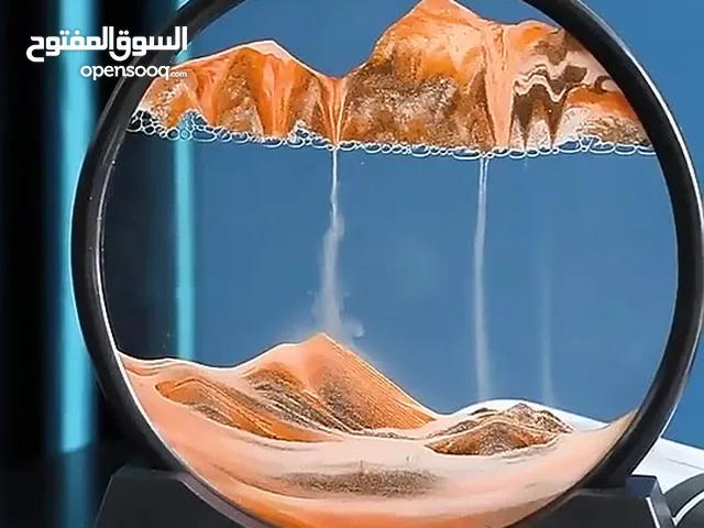 ساعة رملية دائرية باللون البرتقالي الرملي ذو شكل جبال متحركه ومياه بالداخل