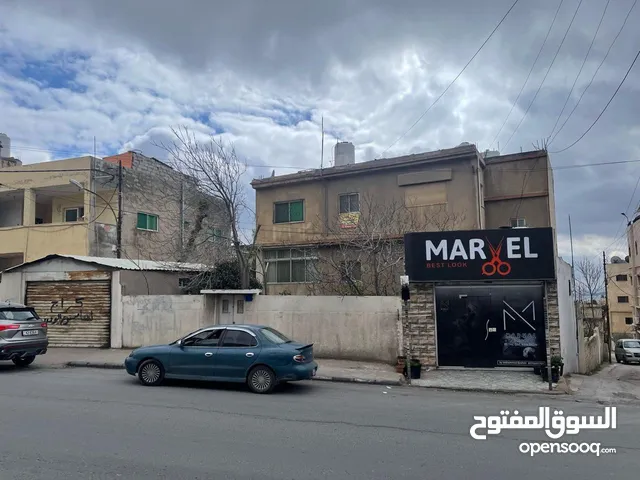 أرض تجاري مساحة 760م عليها بناء سكني مكون من 4 شقق ومحلين للبيع في شارع حيوي في ابو علندا