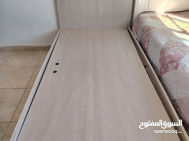 غرفه نوم سرير مفرد مع بوكس خشب لون لولي وسرير ابيض خشب مع فرشه عدد 1 وكومدينه بين التختين وبيرو