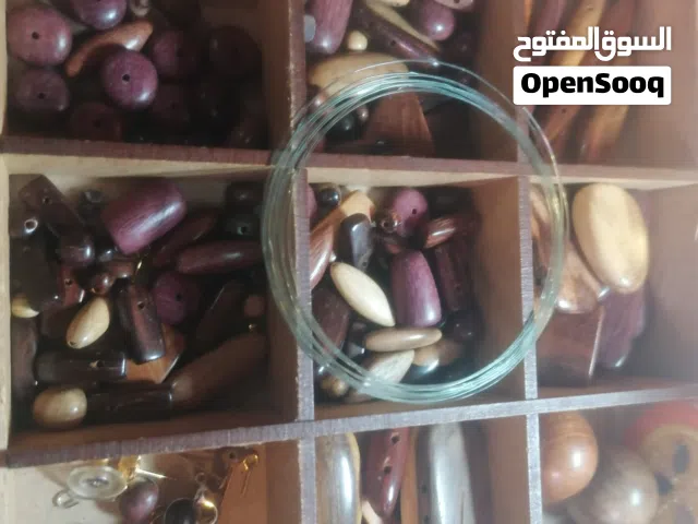 مجموعة متنوعة من لوازم صناعة المجوهرات منظمة داخل صندوق خشبي مقسم. تشتمل هذه المجموعة على خرز خشبي