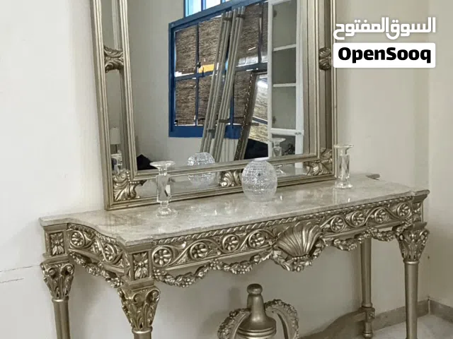 كونسول خشب محفور، لون ذهبي أنتيك، سطح رخام ومرآة كبيرة.