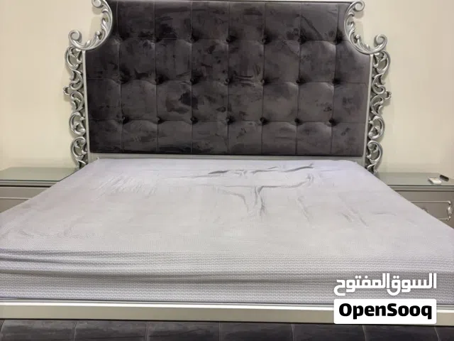 سرير ملكي فاخر جدا بقاعدة خلفية من المخمل والخشب مع ملاحقاتها لونه رمادي فاتح على فضي